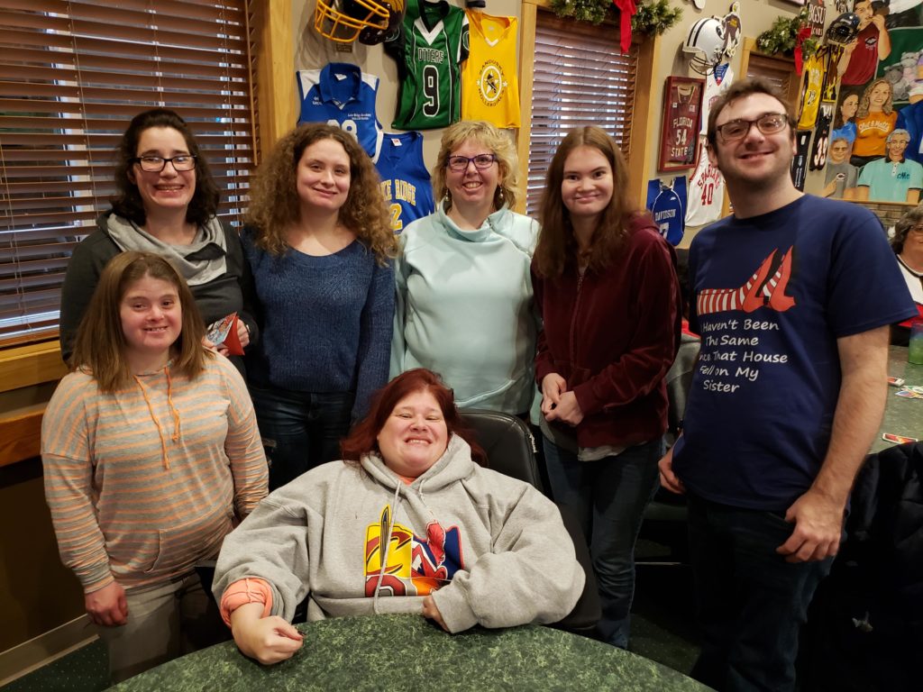 A group of people posing for a picture and standing around a restaurant table