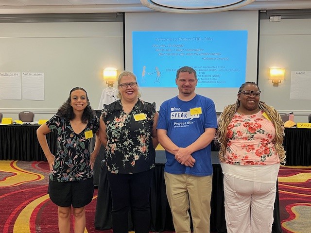 A group of individuals standing in front of a projector for a leadership conference