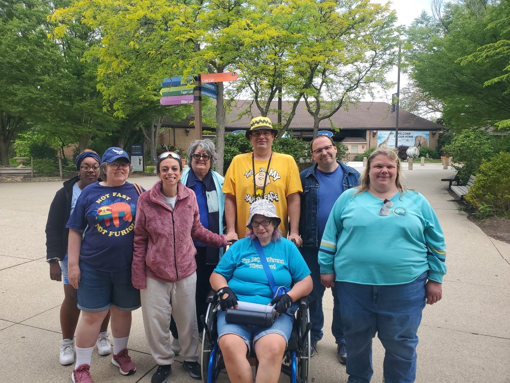 A group of adults standing in a group outside in front of a sign