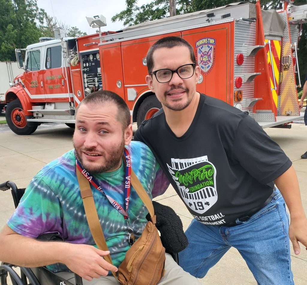 Two adult men standing in front of a fire truck