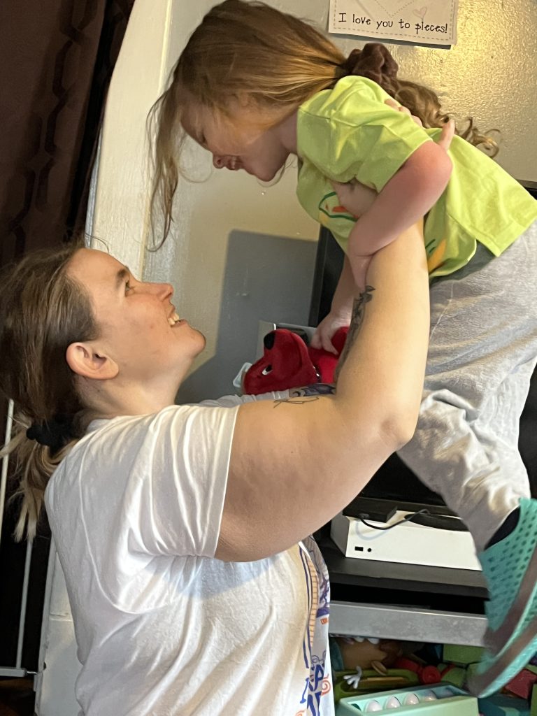 A parent playfully lifting their child in the air