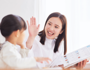 Woman and child reading a book. Woman is giving the child a high five for the job well done