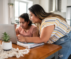 A woman helping another woman on the computer