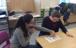 Two women using a communication board while sitting at a table